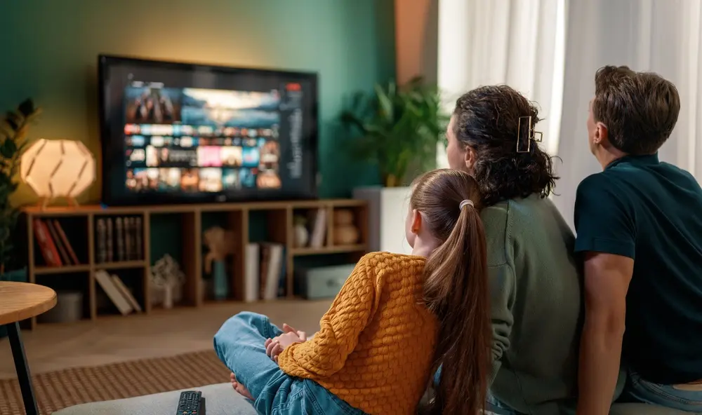 A family of three watching TV together.