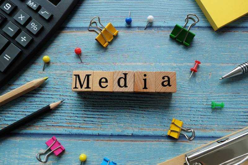 Wooden blocks spelling the word 'MEDIA' arranged on a blue background